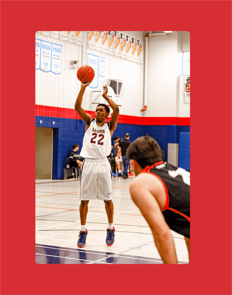A basketball player wearing a white Lions jersey with the number 22 takes a free throw shot, while another player in a black jersey prepares to rebound on a gym court.